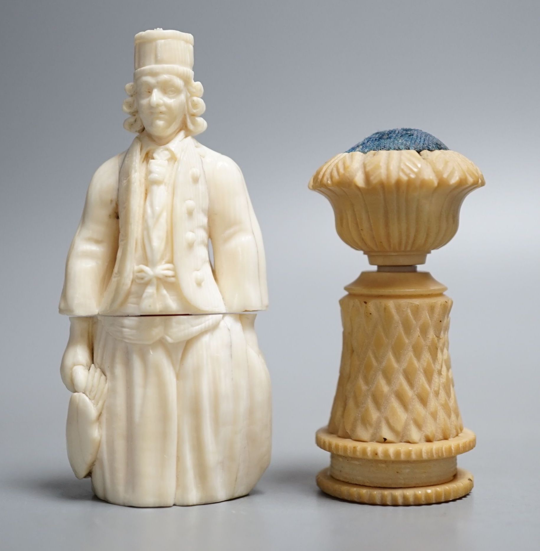 A Dieppe ivory figural needle case, vegetable ivory sewing tape and pin cushion, 19th century